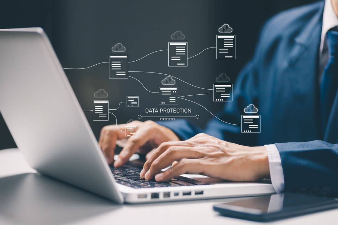 Business professional working on a laptop with cloud data and cybersecurity technology